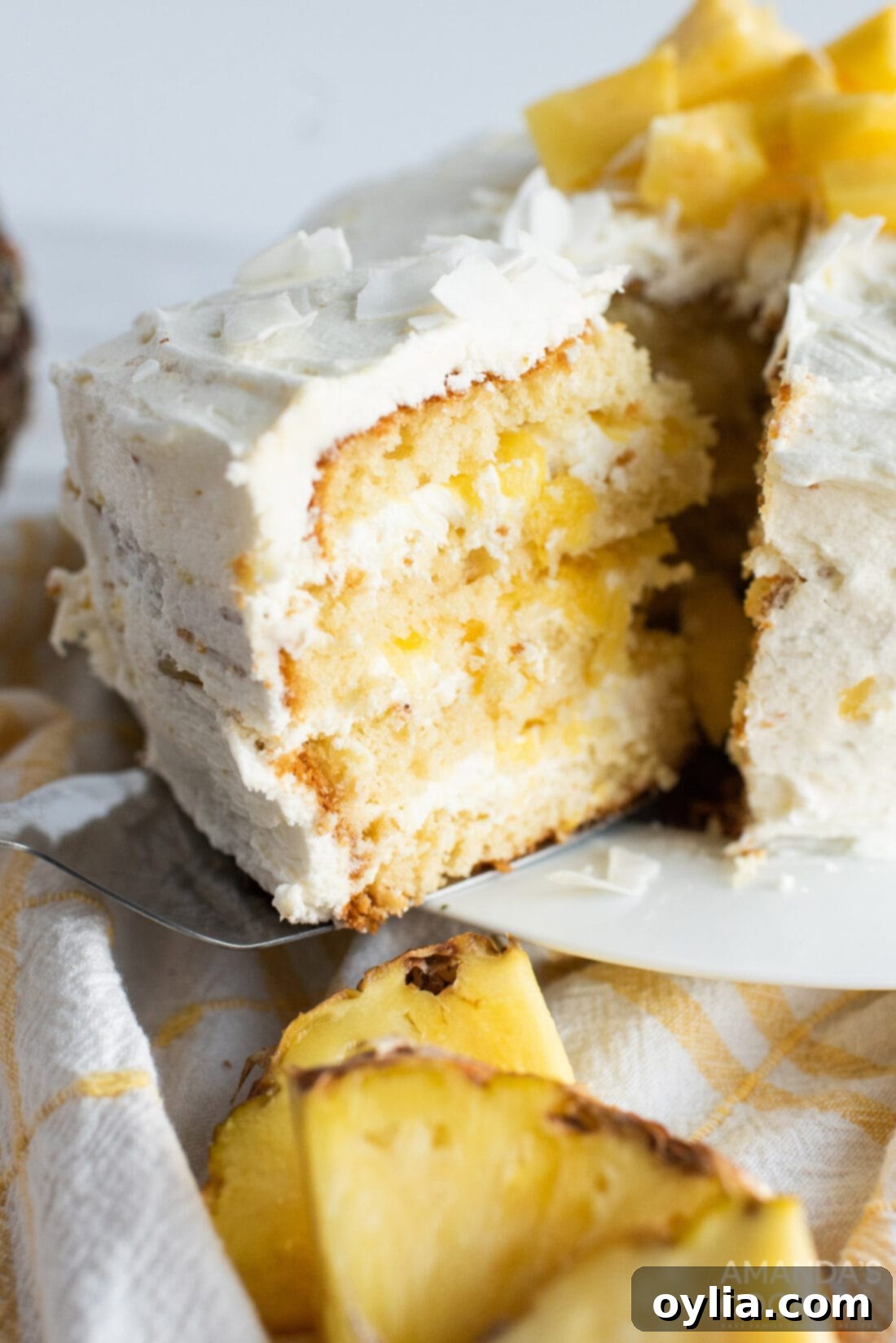 A slice of our beautiful Tropical Pineapple Cake being removed, showcasing its moist layers and creamy frosting.