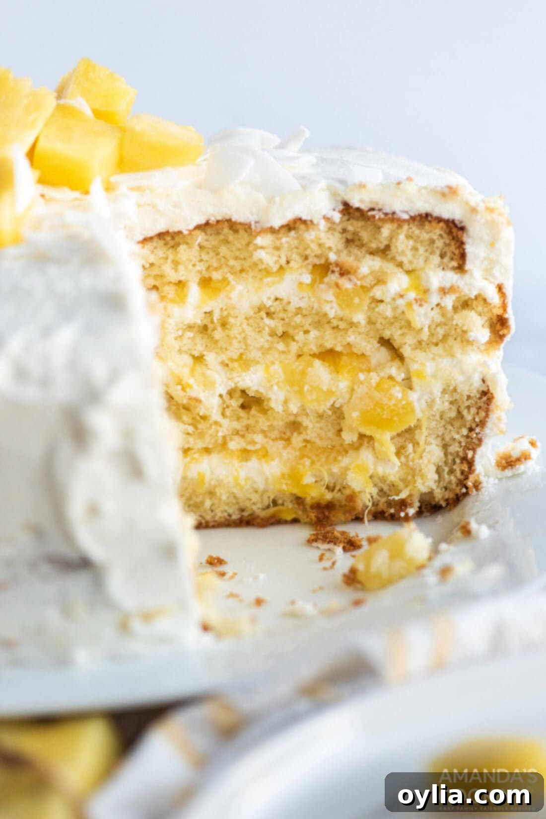 A delectable Pineapple Cake with a slice removed, showing off its moist interior and tempting layers of filling and frosting.