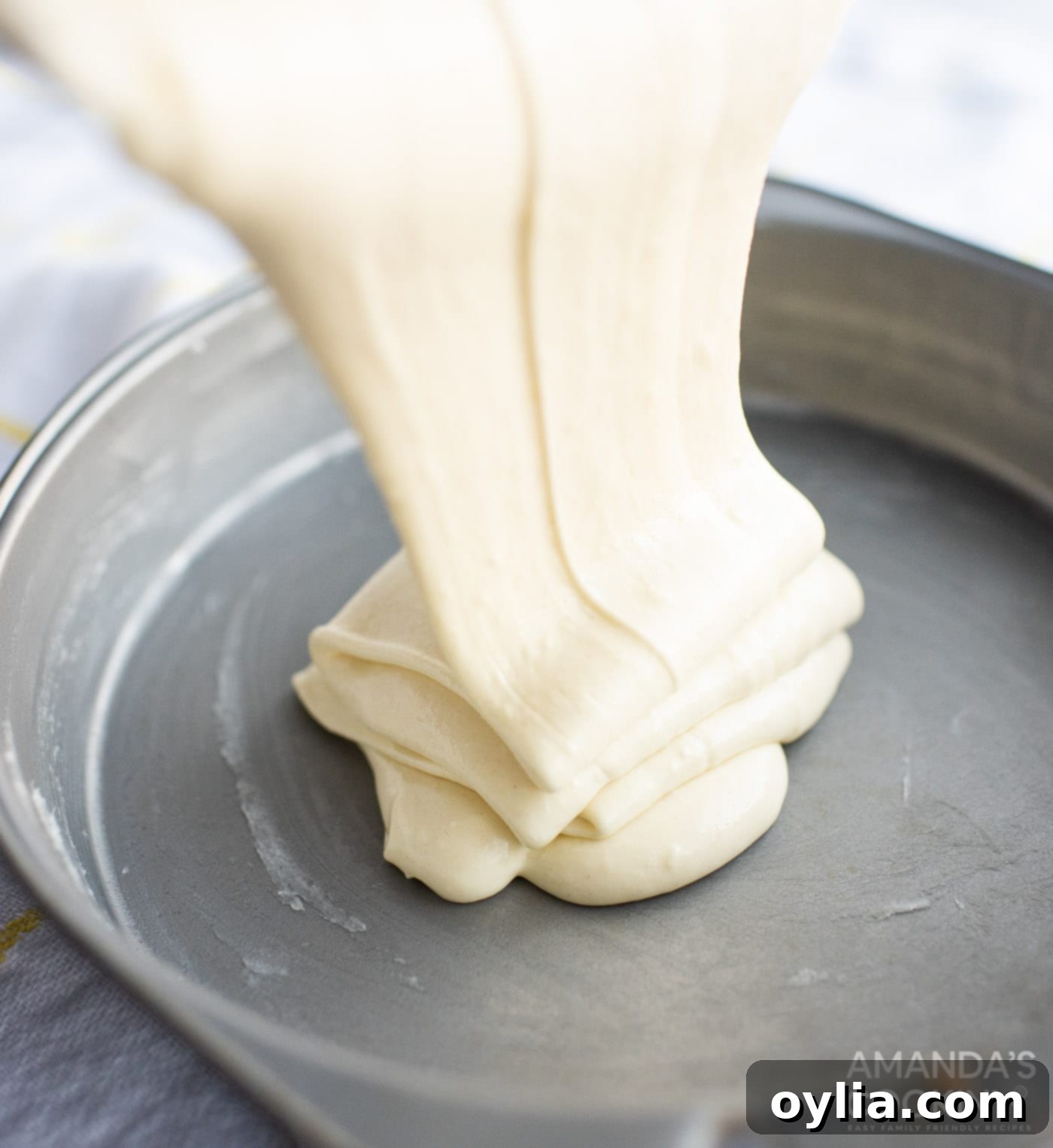 Pineapple cake batter being poured into round cake pans for baking.