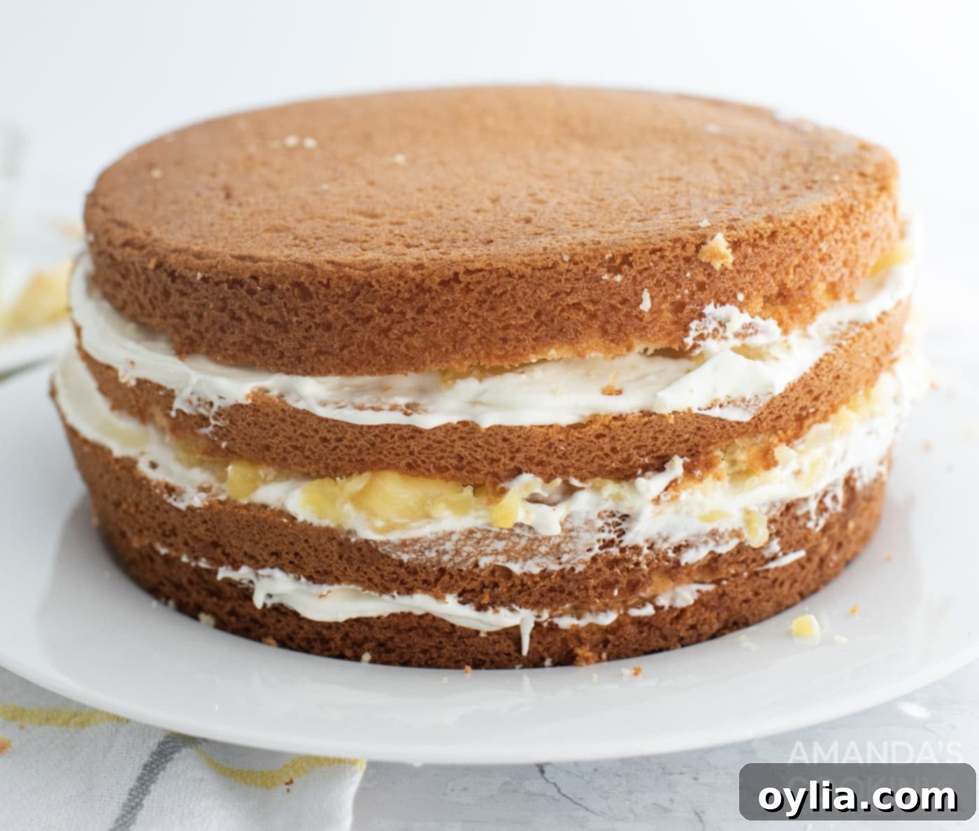 A four-layered pineapple cake, assembled and ready for the final frosting, showing distinct cake and filling layers.