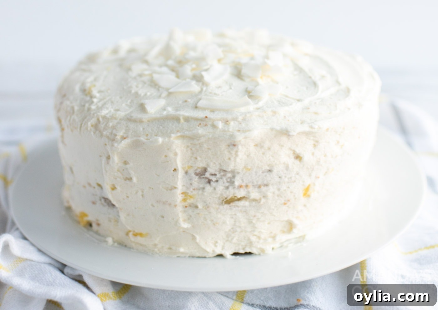 A fully frosted Pineapple Cake, beautifully decorated with shredded coconut, ready for garnishing.