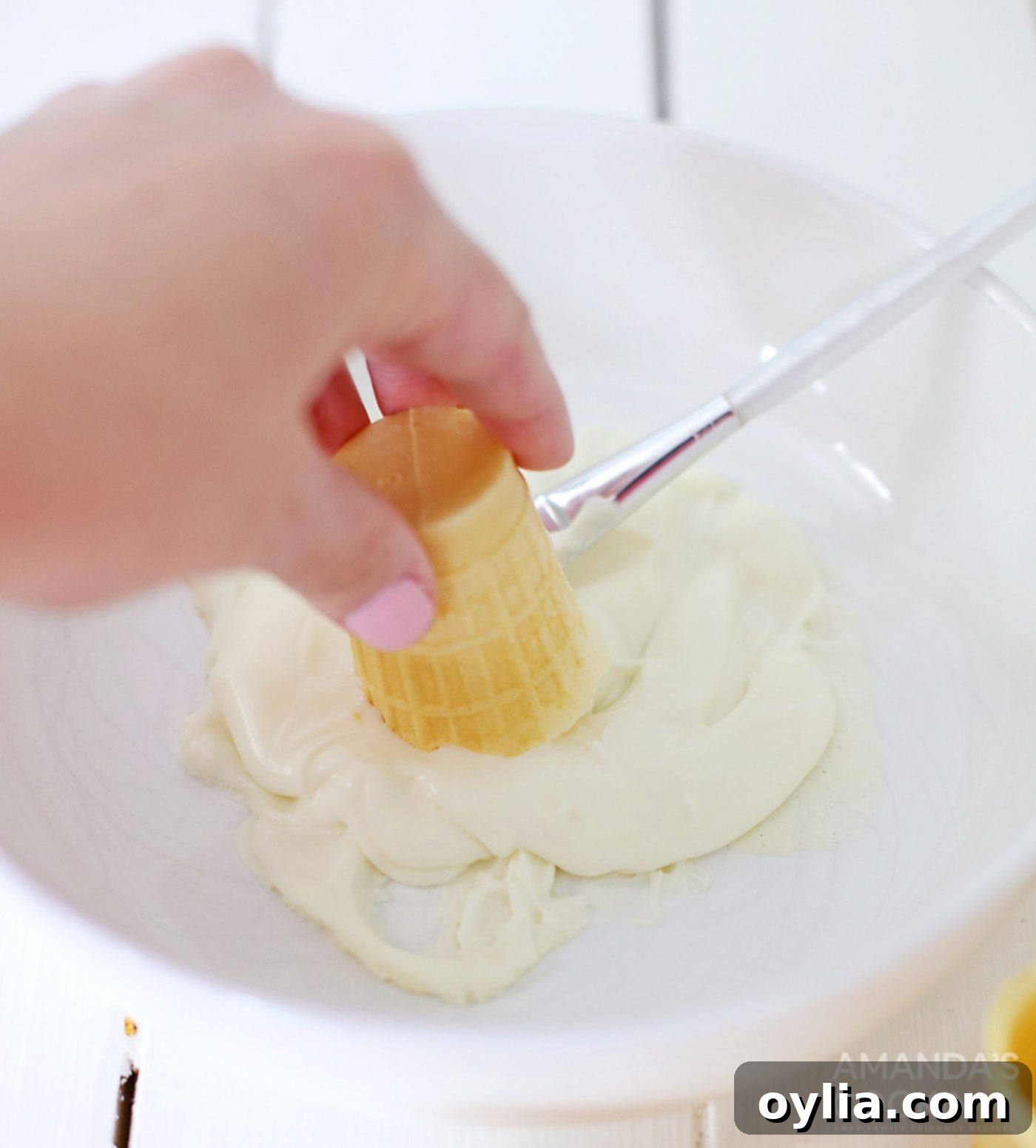 Dipping an ice cream cone in melted white chocolate for coating