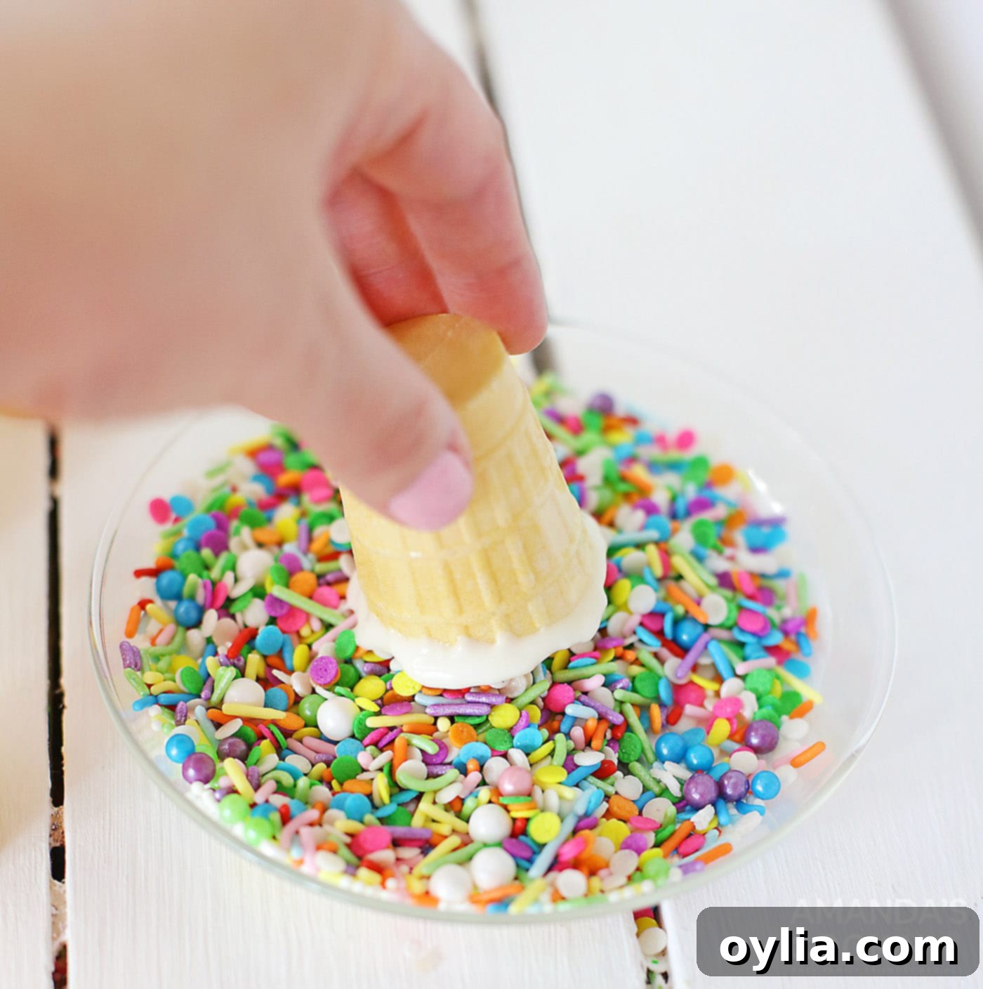 Dipping a chocolate-coated ice cream cone rim into colorful sprinkles