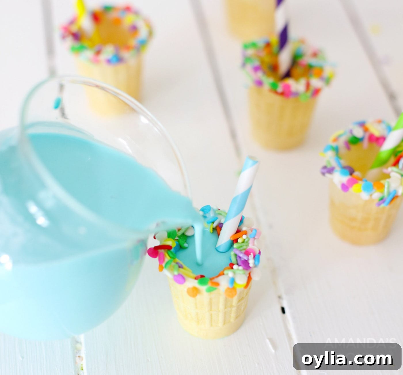 Pouring blue RumChata mixture into decorated ice cream cone shot glasses