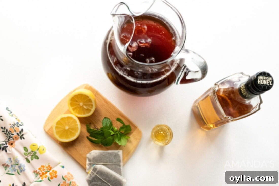 Spirited Tea Cooler 4 ingredients laid out for making an iced tea cocktail, including honey whiskey, iced tea, lemon, and mint