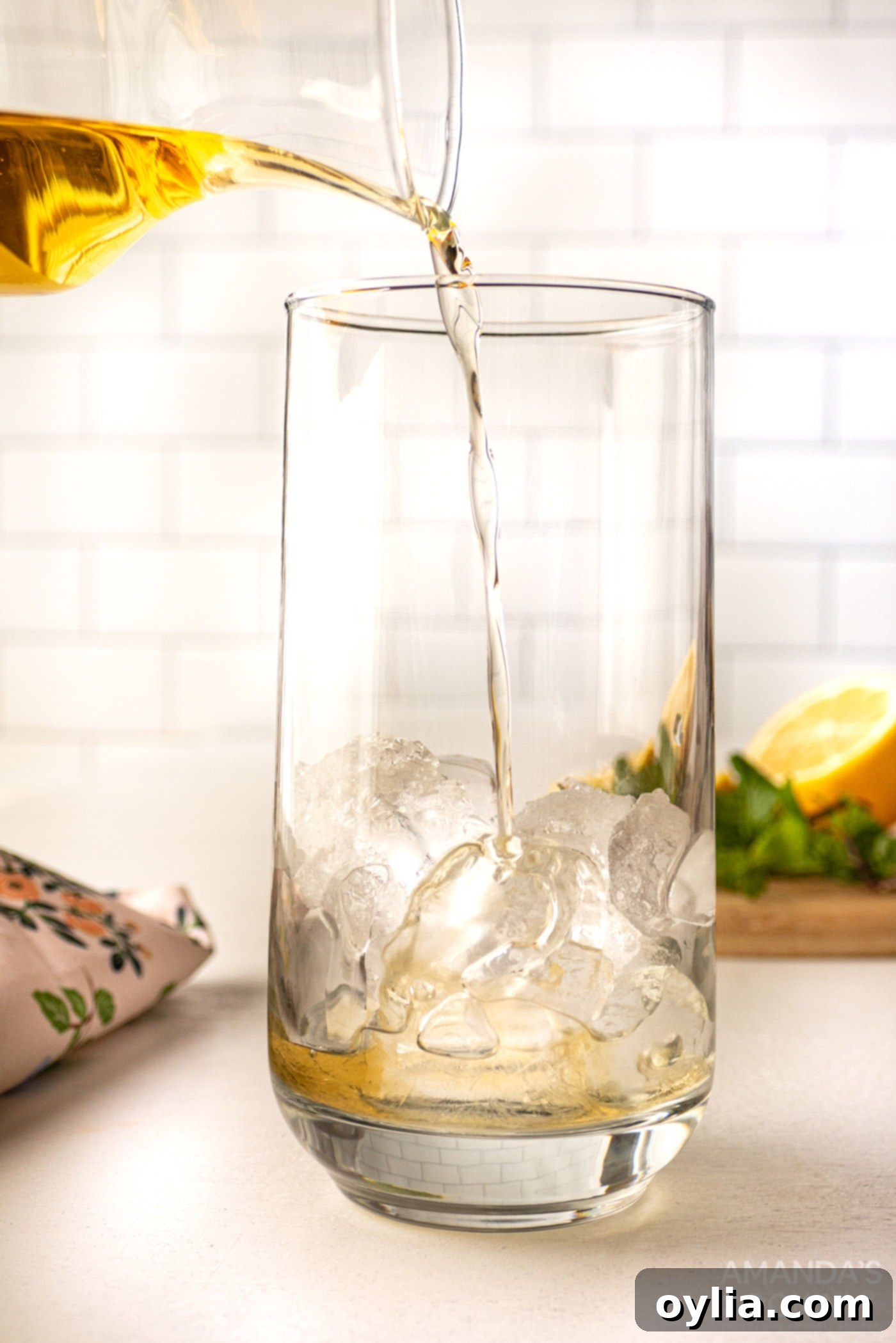 pouring honey whiskey into a glass filled with ice
