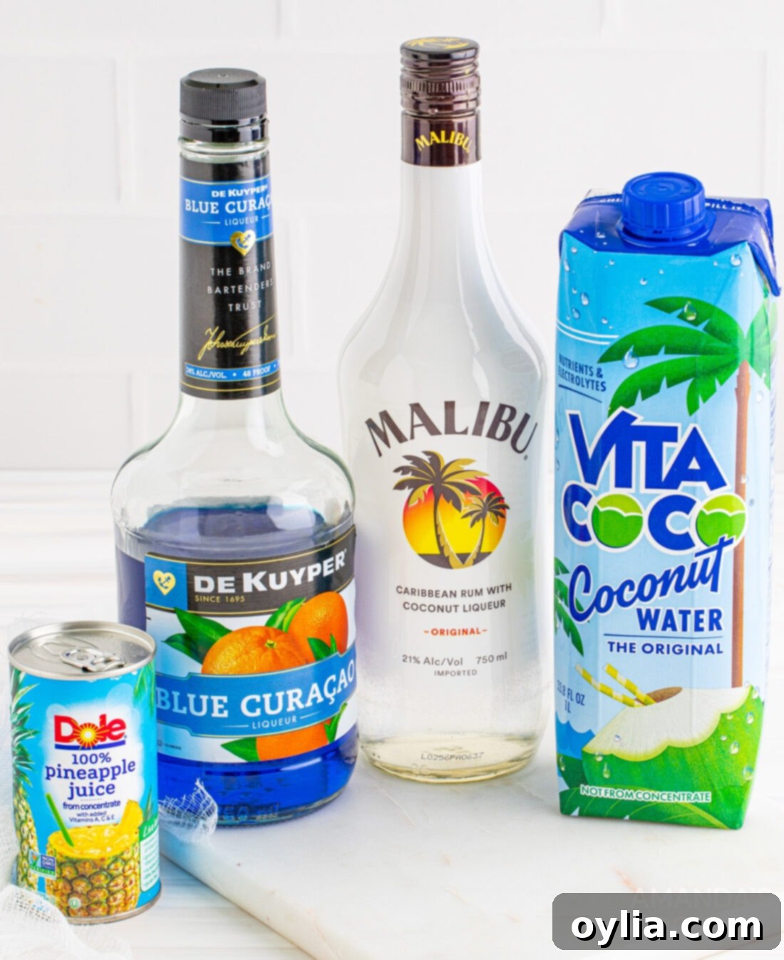A flat lay of ingredients for the Ocean Water Cocktail, including bottles of rum, blue curacao, and fresh pineapple.