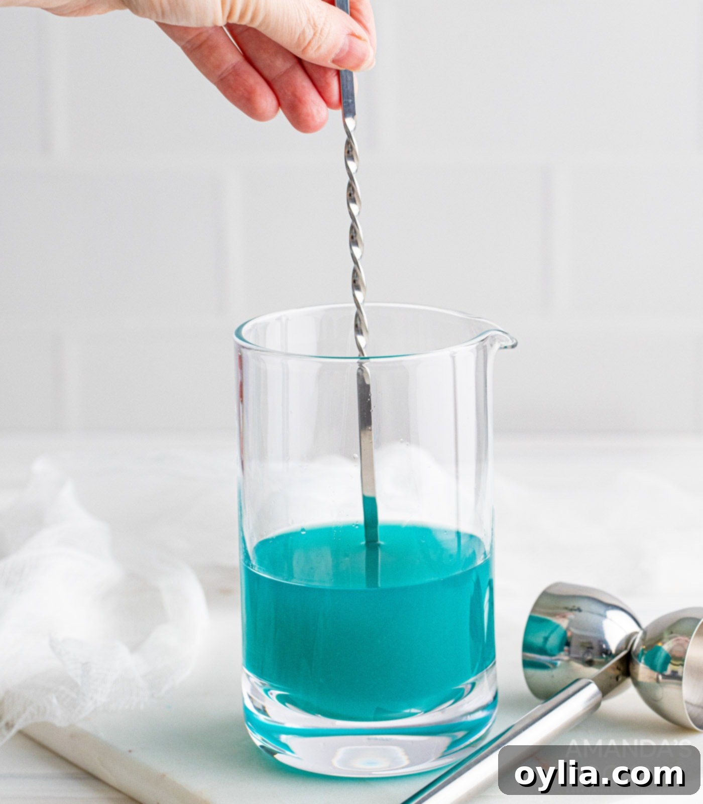 mixing liquor ingredients in a glass with a cocktail spoon