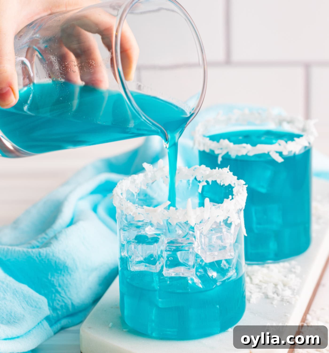 pouring the mixed ocean water cocktail into a glass filled with ice and garnishes