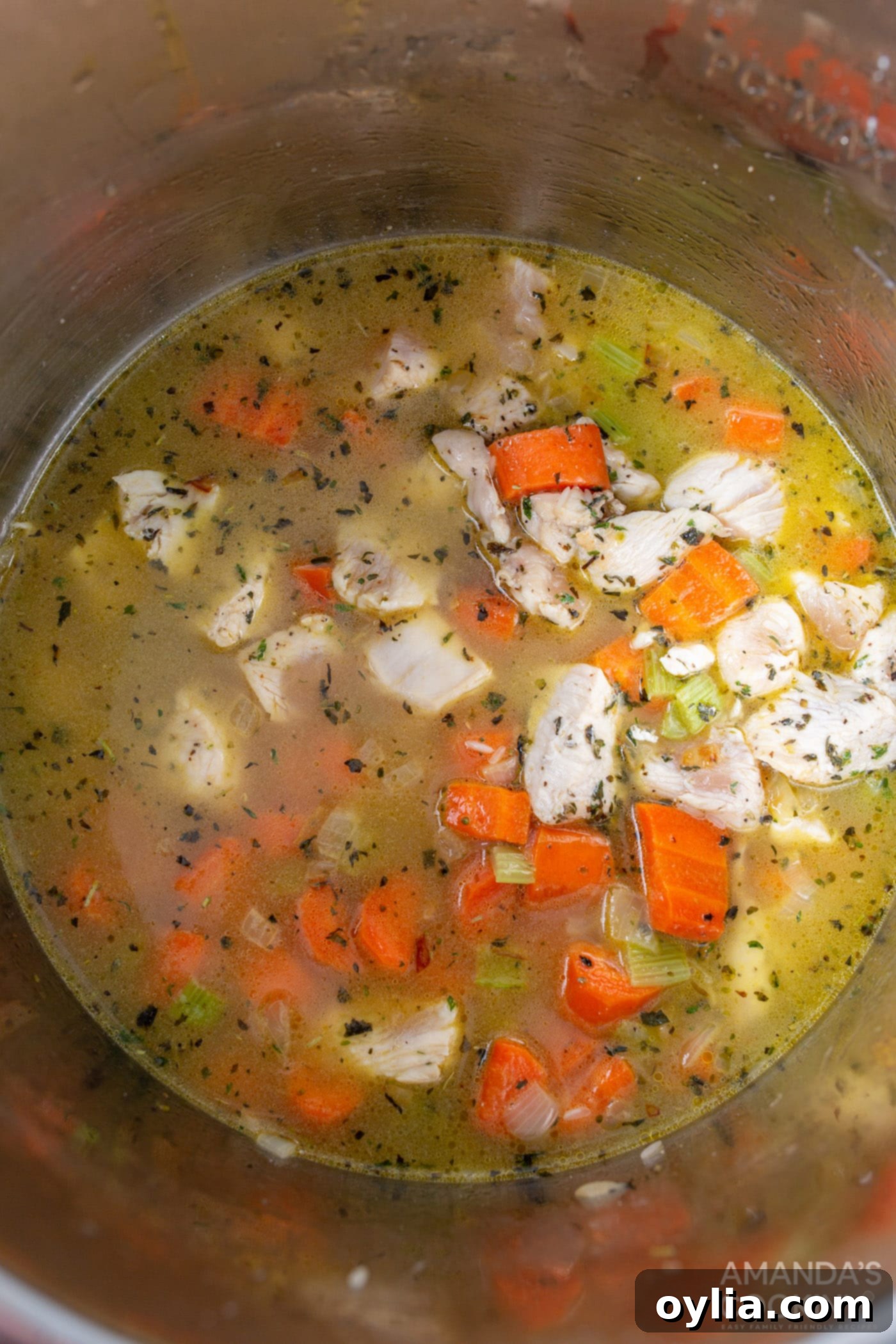 Chicken stock being poured into the Instant Pot over the chicken, rice, and vegetables mixture.