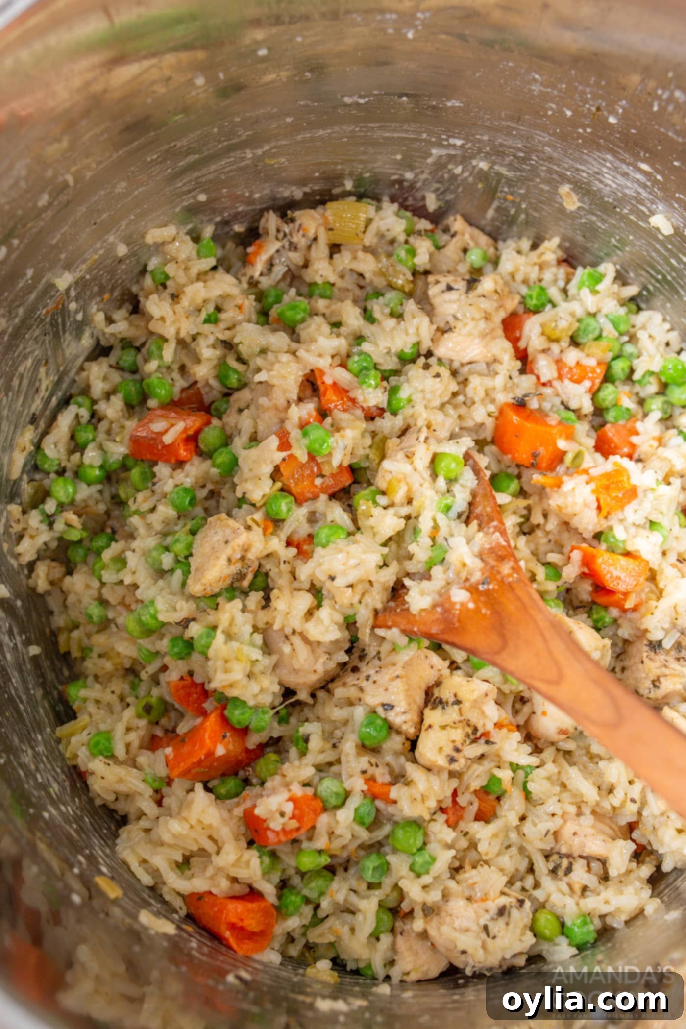 Stirring the cooked Instant Pot chicken and rice with added peas, creating a vibrant and ready-to-serve dish.