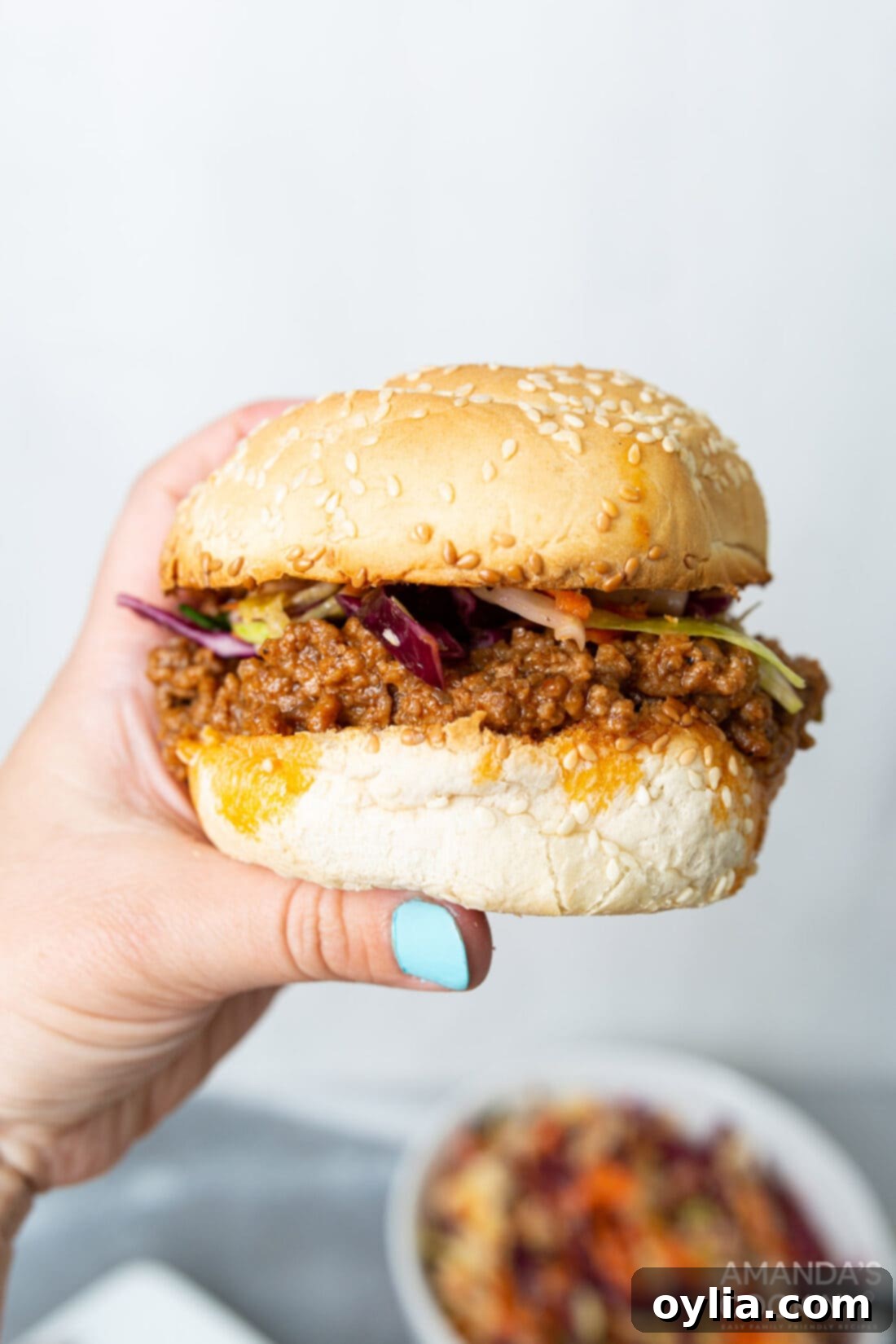 A hand holding a savory Instant Pot Sloppy Joe sandwich, showcasing the rich filling and toasted bun.
