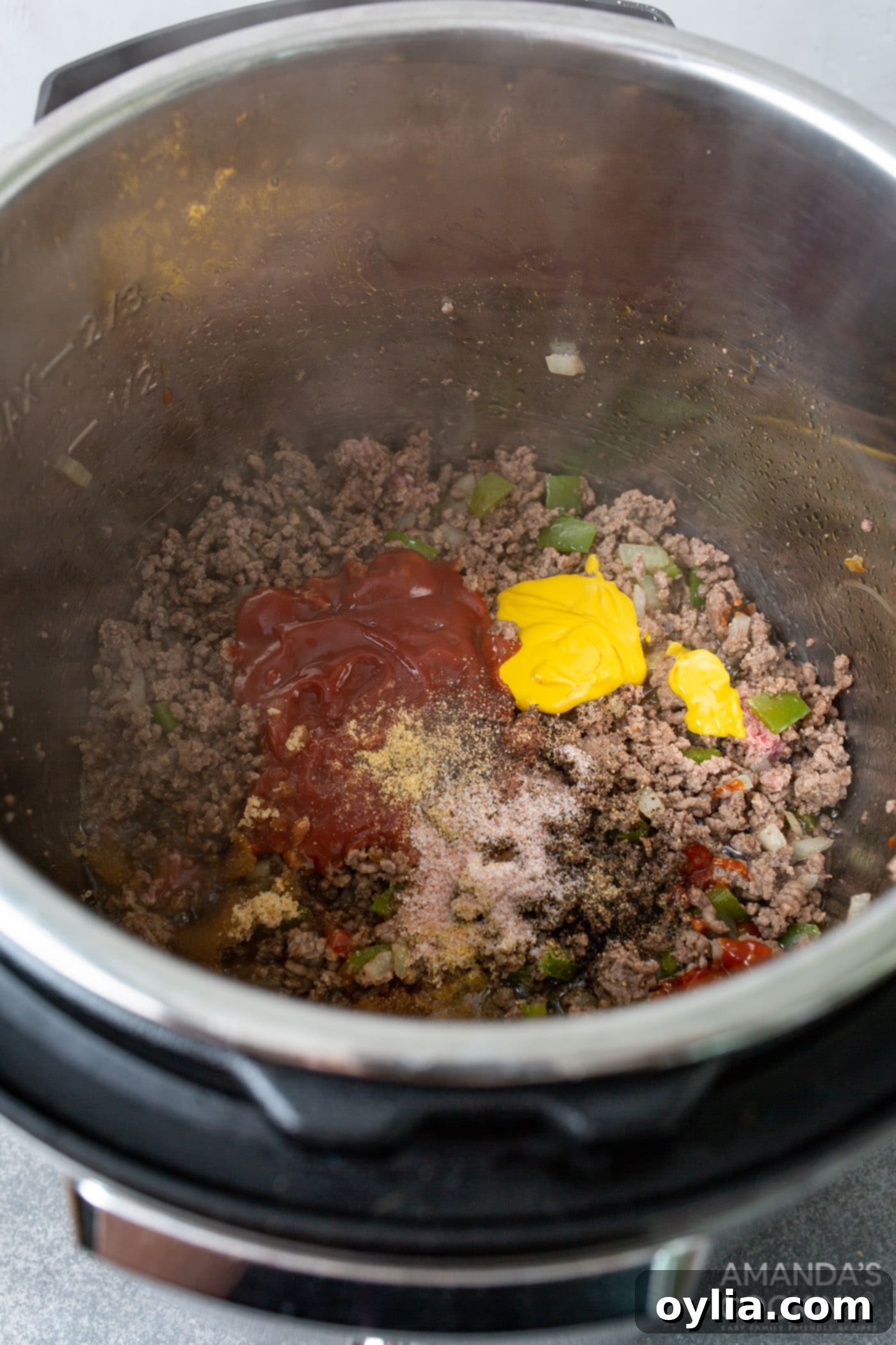 Stirring in seasonings, ketchup, mustard, brown sugar, and water with the browned ground beef and vegetables in the Instant Pot.