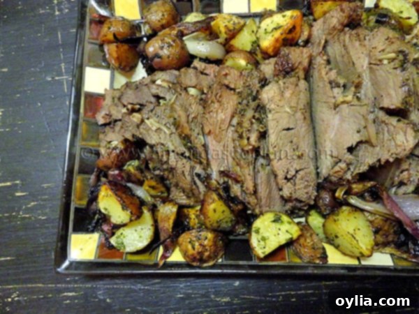 An overhead photo of a Sunday roast on a plate, featuring sliced sirloin beef, roasted potatoes, onions, and mushrooms, drizzled with gravy.
