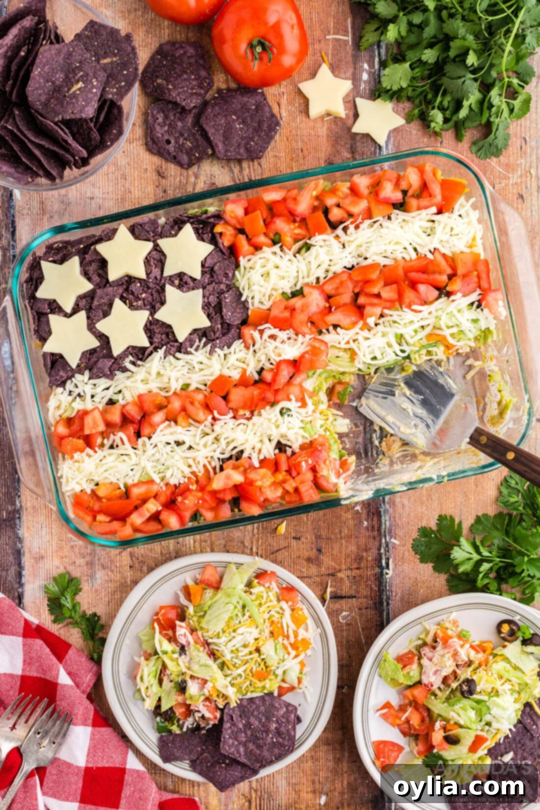 A vibrant taco salad designed as an American flag, with red tomato stripes, white mozzarella stripes, and a blue corner of crushed tortilla chips adorned with star-shaped cheese cutouts.