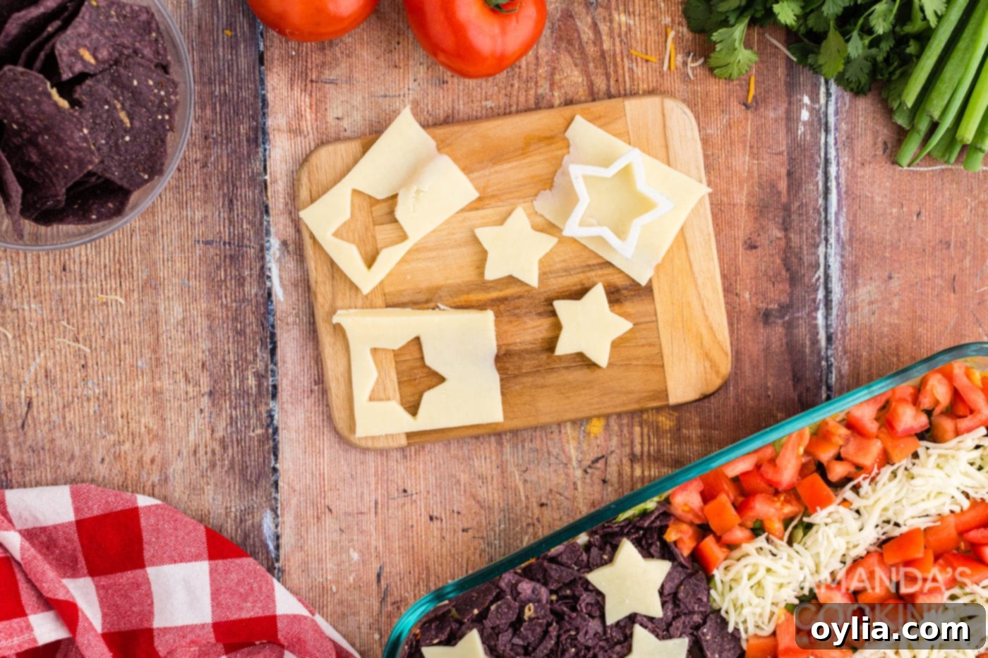 White star shapes precisely cut from cheese slices and arranged on top of the blue corn chips, completing the American flag design on the taco salad.