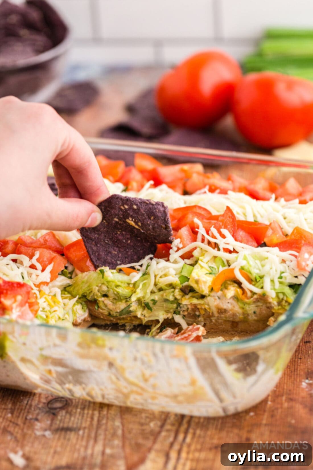 A hand scooping a generous portion of the Patriotic Taco Salad Flag with a tortilla chip, showing all the delicious layers.