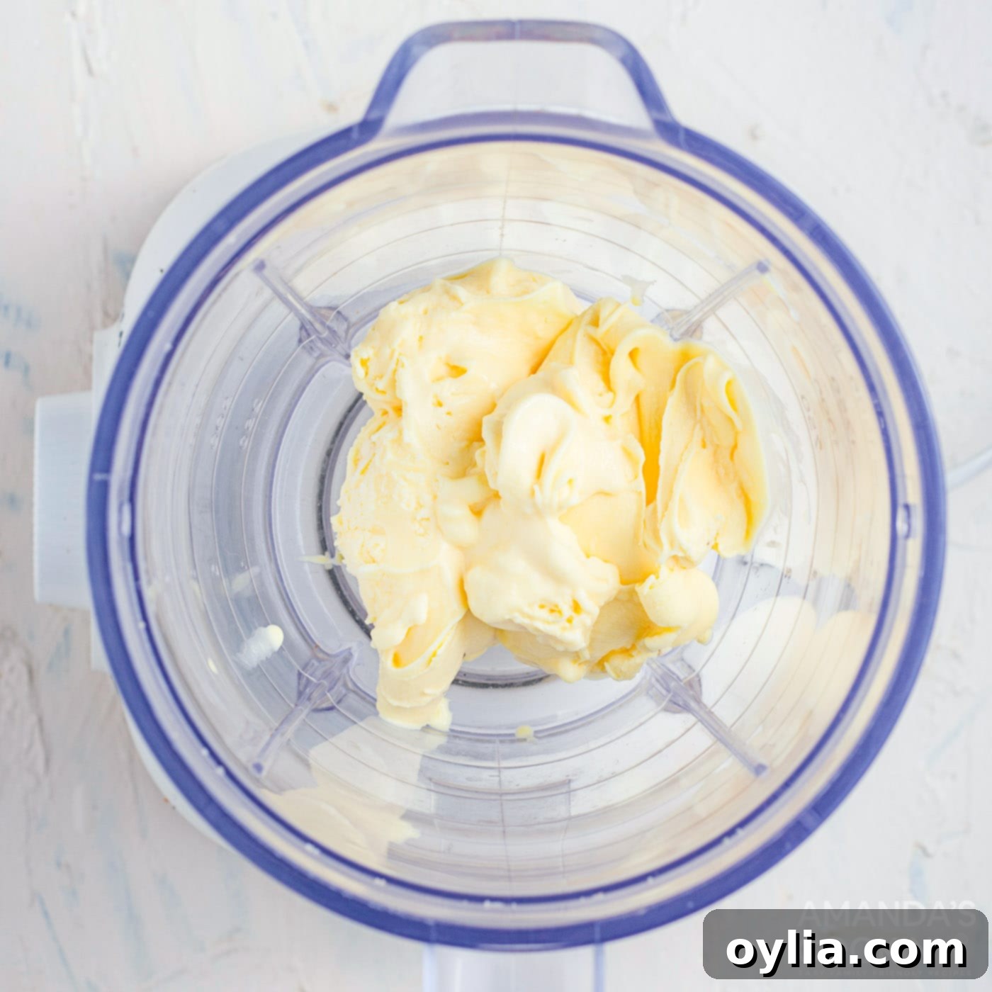 Blender with ice cream, milk, and vanilla extract, ready to be blended for a salted caramel milkshake.
