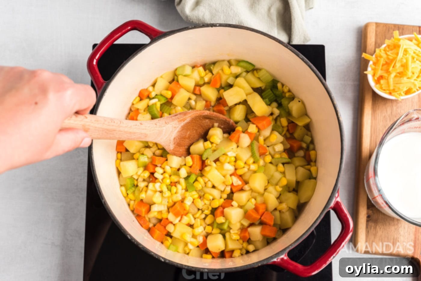 A close-up view of corn chowder soup simmering in a saucepan, with visible vegetables.