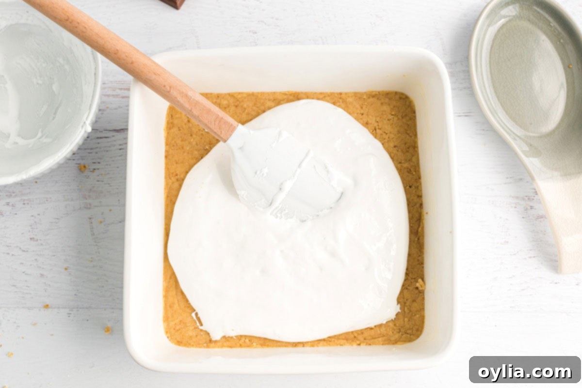 spreading marshmallow creme over dough in pan