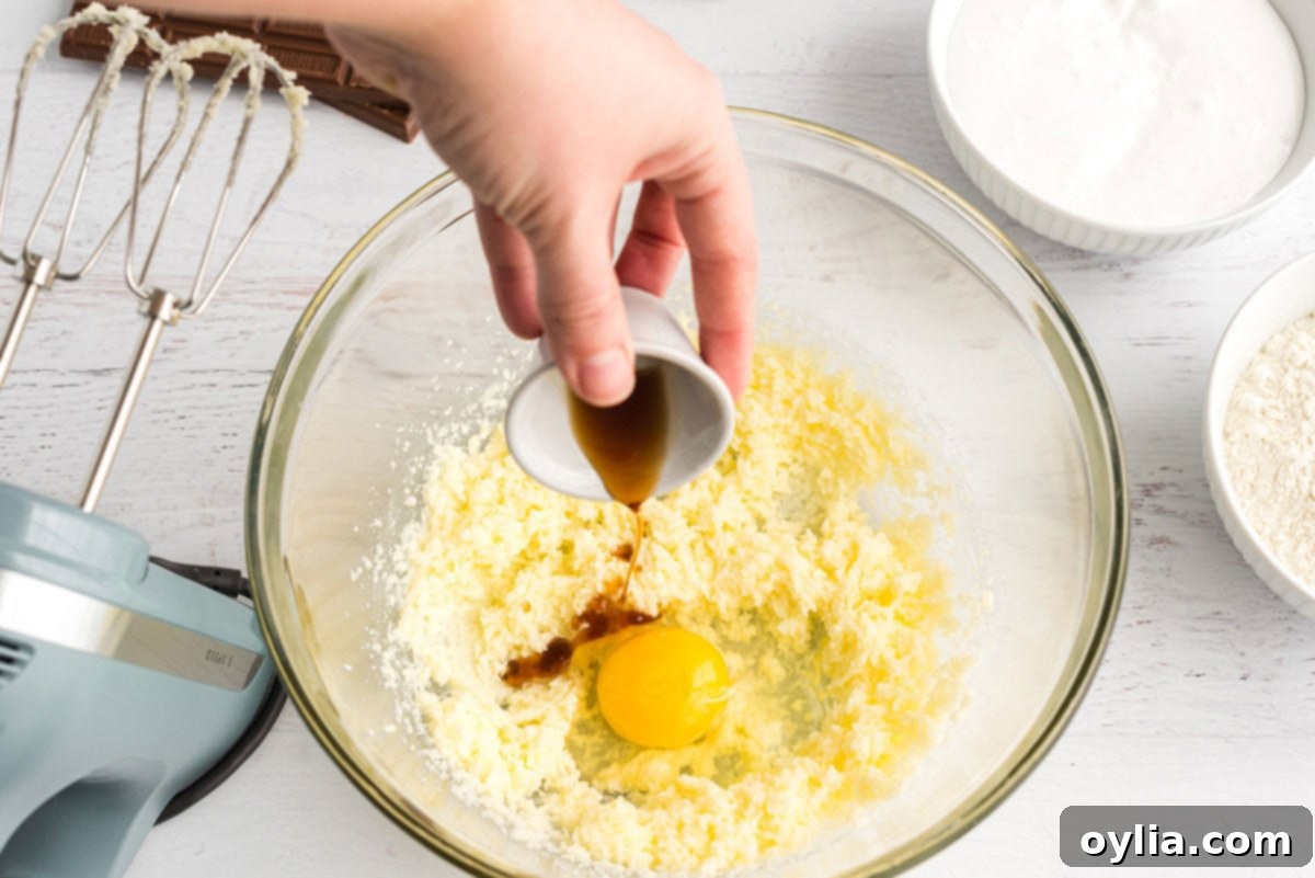 adding vanilla to eggs in bowl with butter and sugar