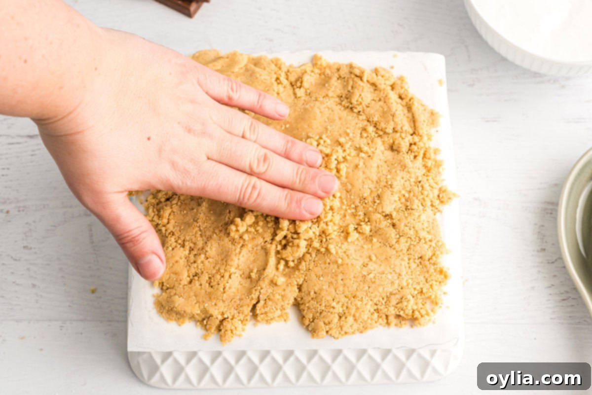 hand spreading half of the dough on waxed paper