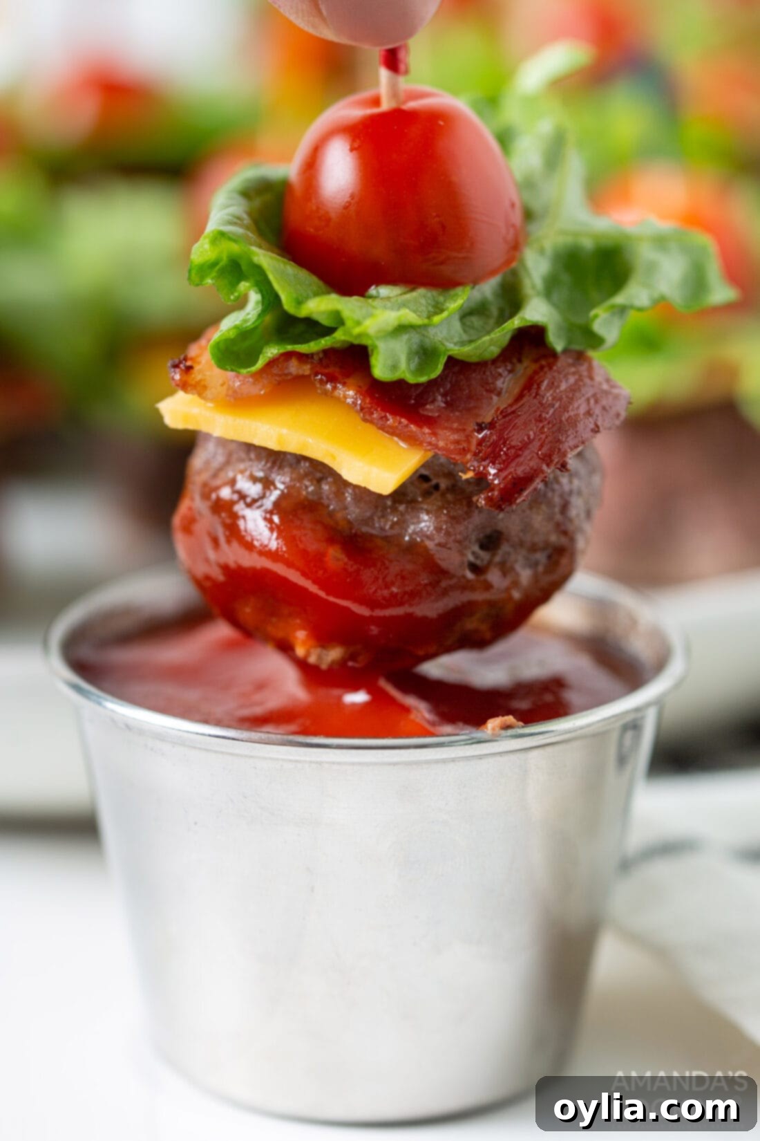 dipping a Bacon Cheeseburger Meatball appetizer in ketchup