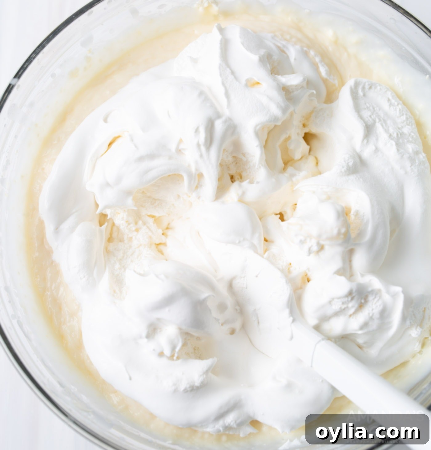 vanilla pudding, cream cheese, and cool whip in a mixing bowl being combined