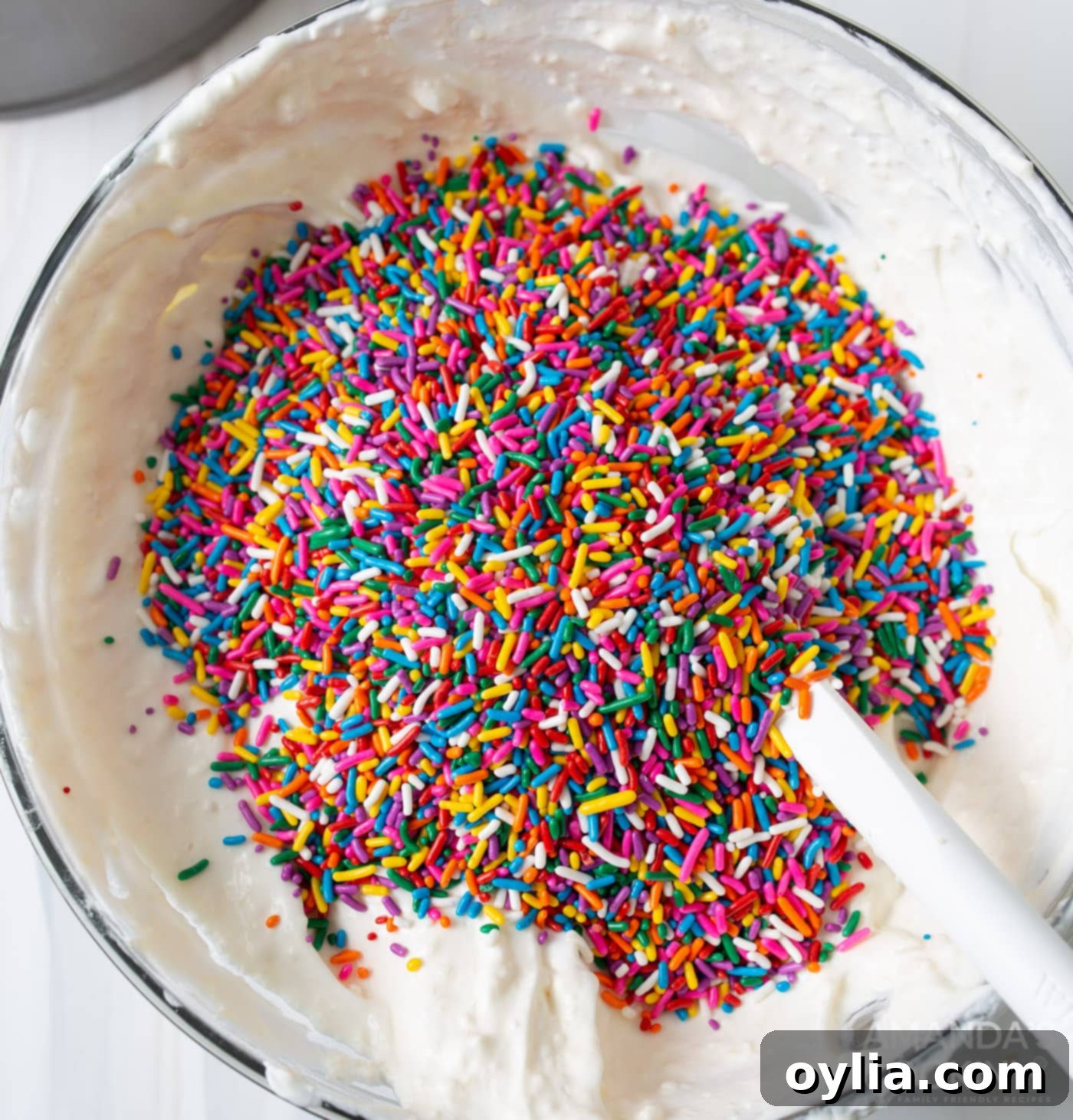 rainbow sprinkles being folded into pudding mixture for Funfetti Icebox Cake
