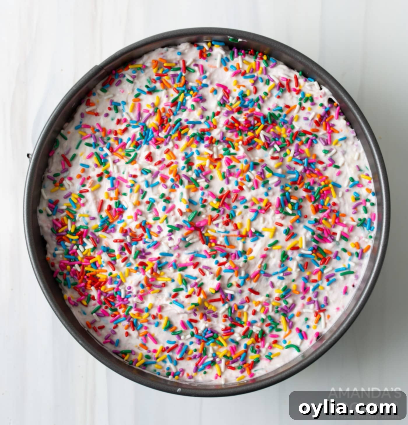 funfetti icebox cake being layered in a pan with sprinkles on top