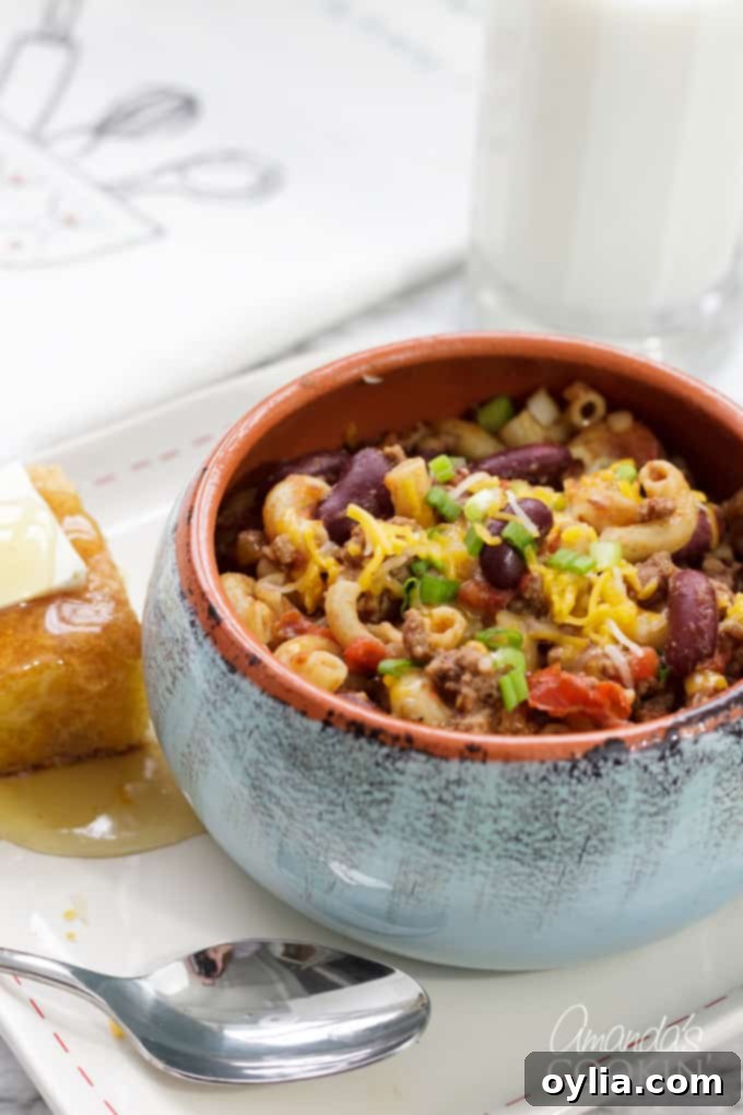 A steaming bowl of classic Chili Mac, garnished with fresh cilantro and shredded cheese, ready to be enjoyed as a hearty meal.
