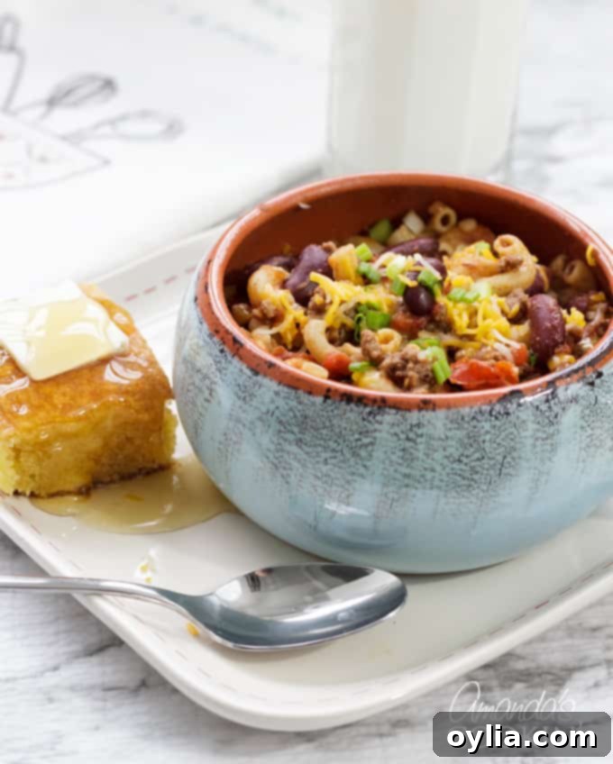 A close-up shot of Chili Mac in a bowl, showcasing the rich chili, beans, and macaroni, with a side of cornbread for dipping.