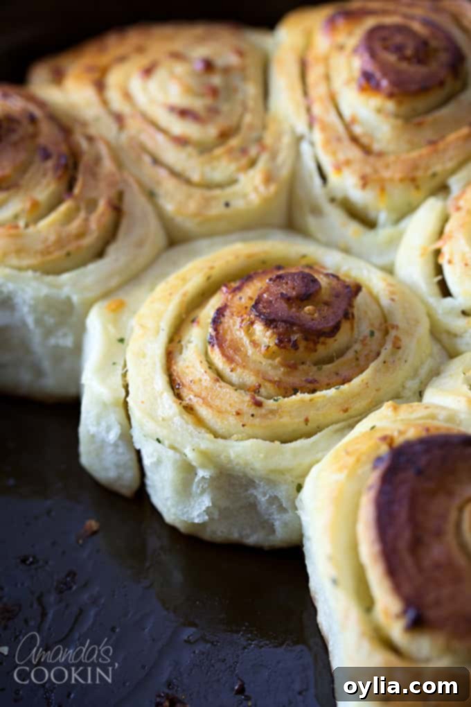 A close up of freshly baked Parmesan garlic rolls, golden brown and glistening with butter.