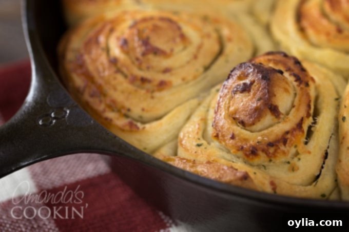 A close up of Parmesan garlic rolls, golden brown and perfectly baked, nestled in a round cast iron pan.