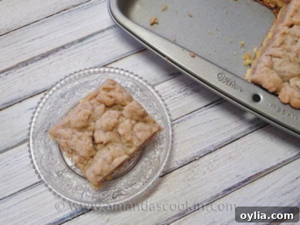 A slice of homemade crumb cake on a clear plate, showcasing the thick crumb topping.