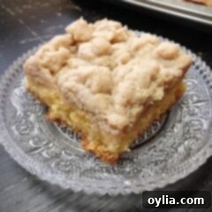 A close up photo of a square of crumb cake on a clear plate.