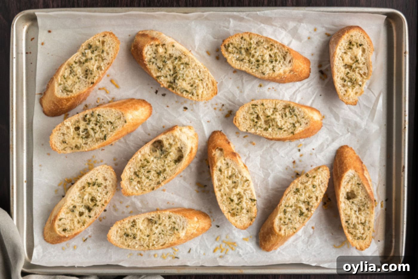 toasted bruschetta bread on a baking sheet with parmesan cheese