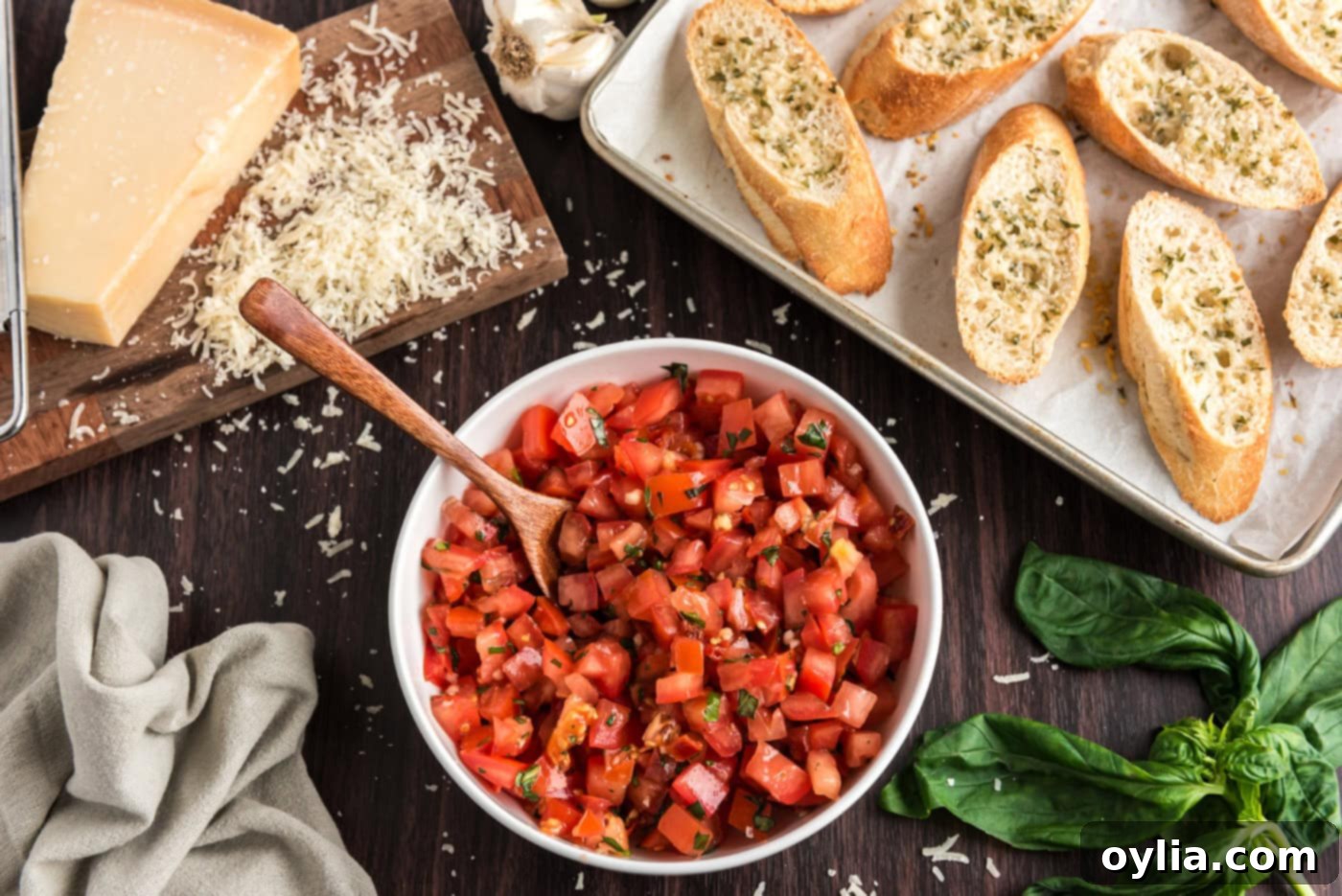 bruschetta tomato mixture in a bowl next to sliced bread with parmesan cheese