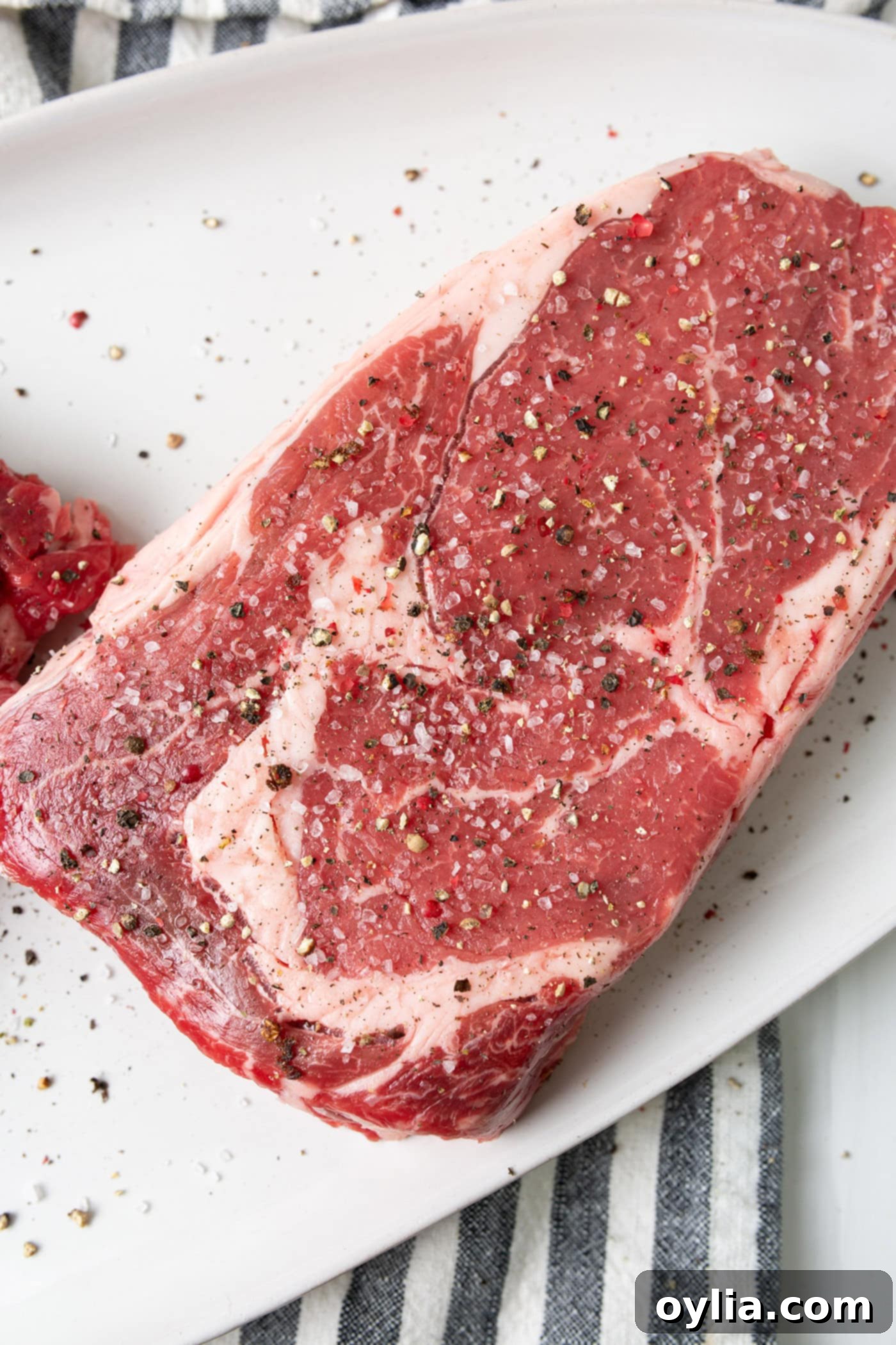 Steak seasoned with salt and pepper on a cutting board.