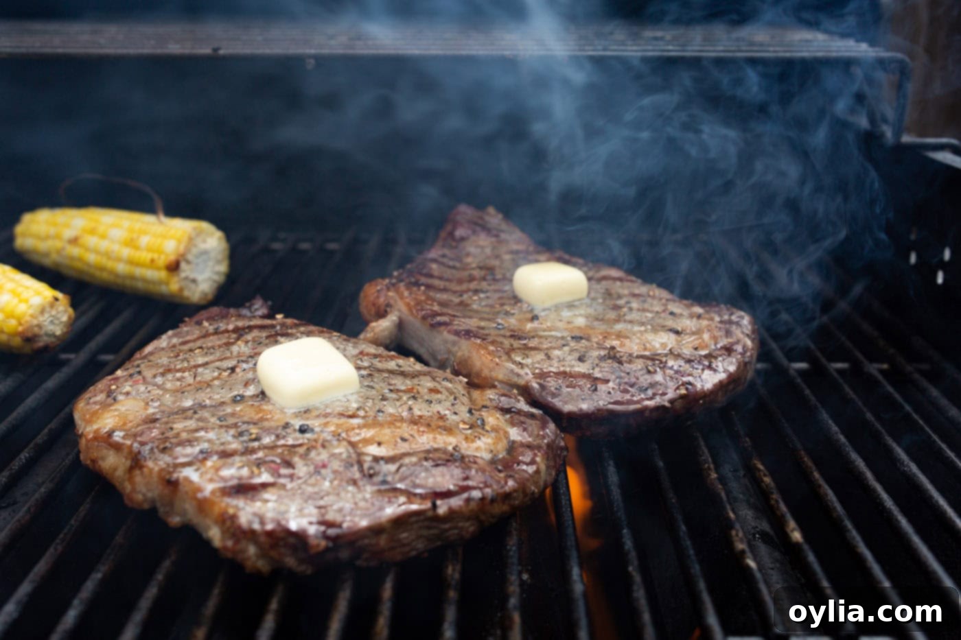 Pats of butter melting on top of grilled New York strip steaks.