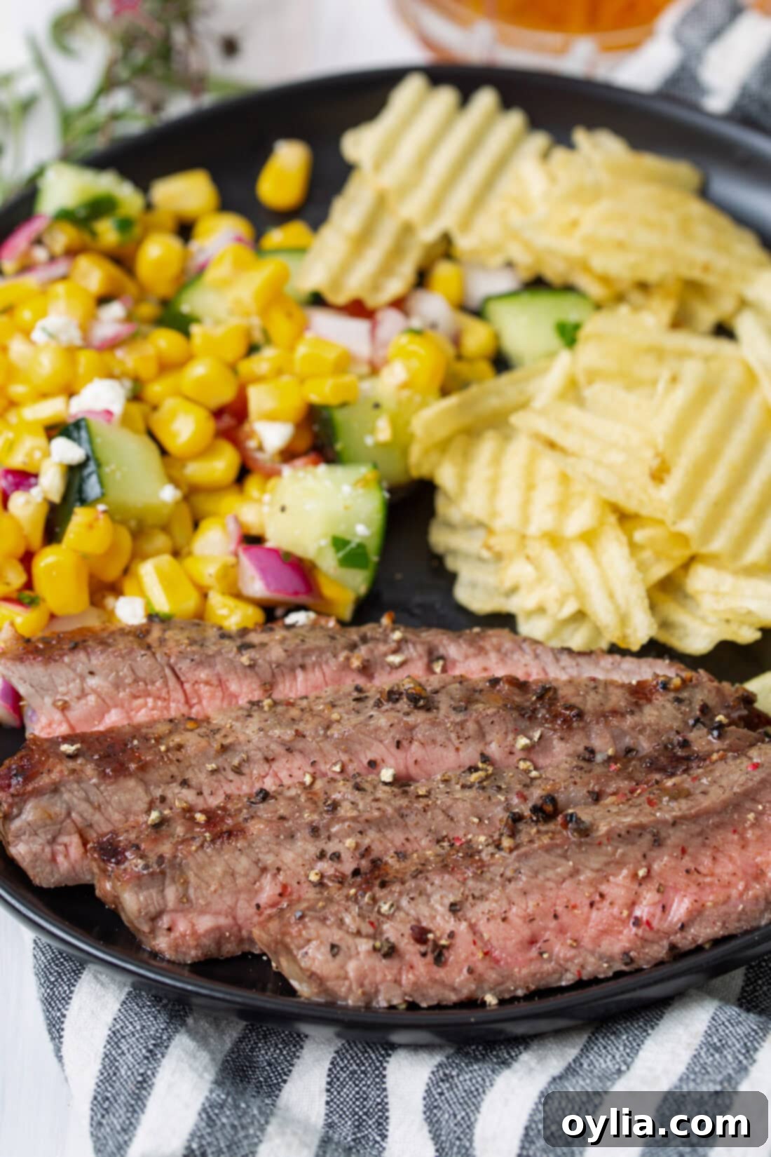 Sizzling Steak Perfection 9 A perfectly grilled New York Strip Steak served on a plate with fresh corn on the cob.