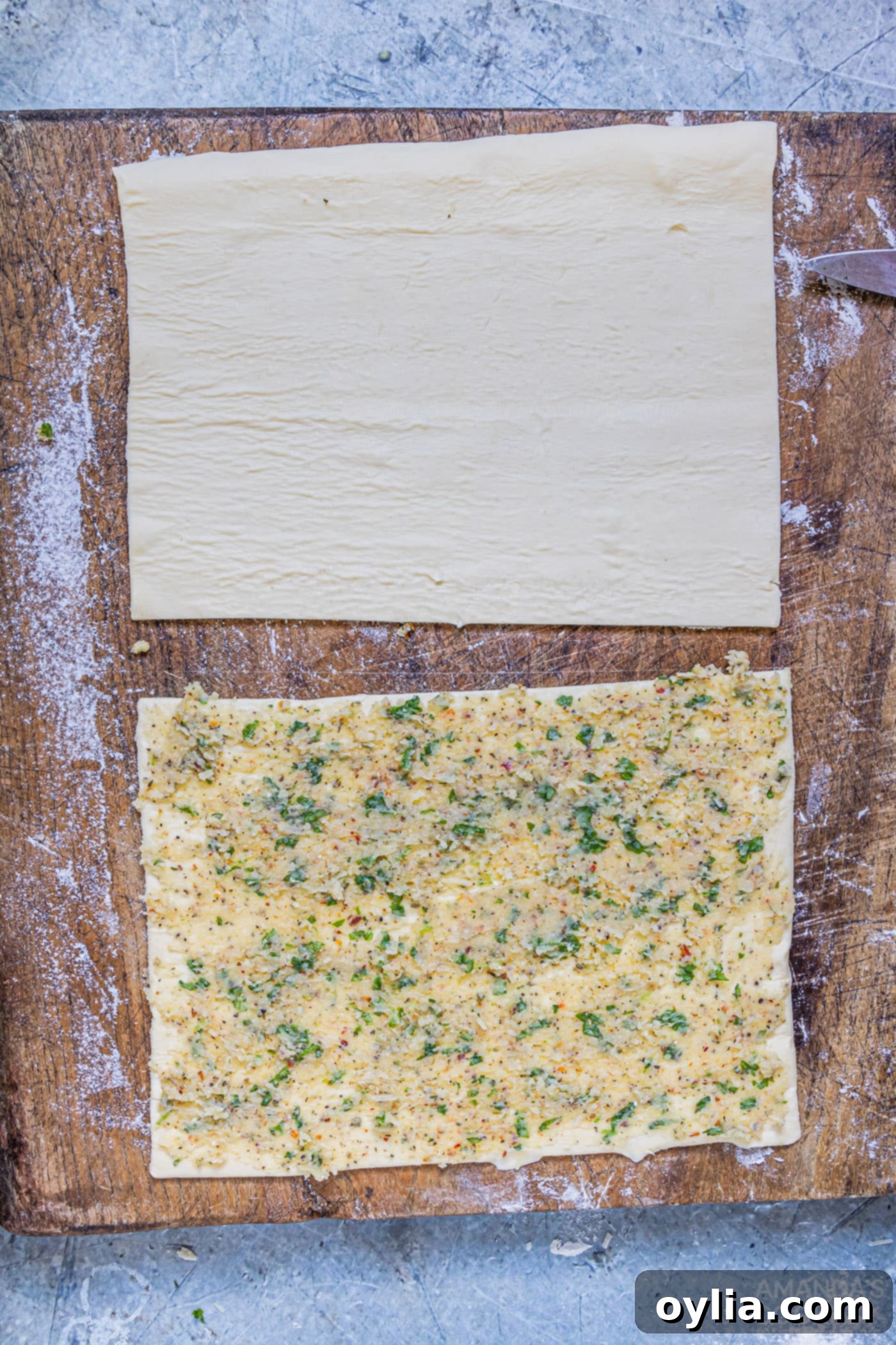 garlic butter smeared onto puff pastry sheet, ready for layering