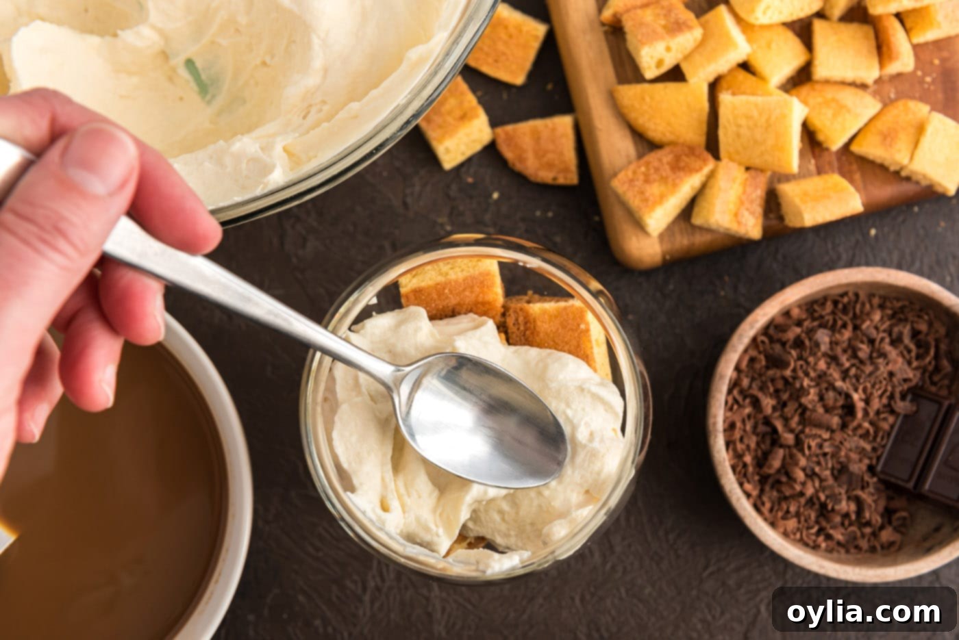 spooning mascarpone cheese mixture over ladyfingers in a dish