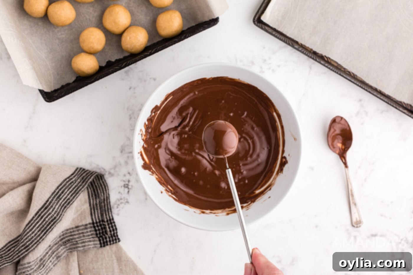 A chocolate-dipped peanut butter ball on a dipping tool, showing the even coating