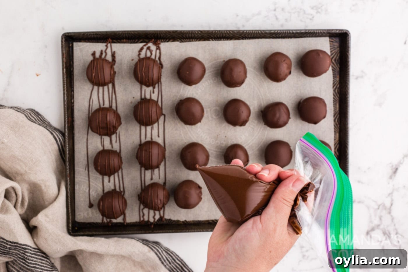 Drizzling melted chocolate over finished chocolate peanut butter balls for an artistic touch