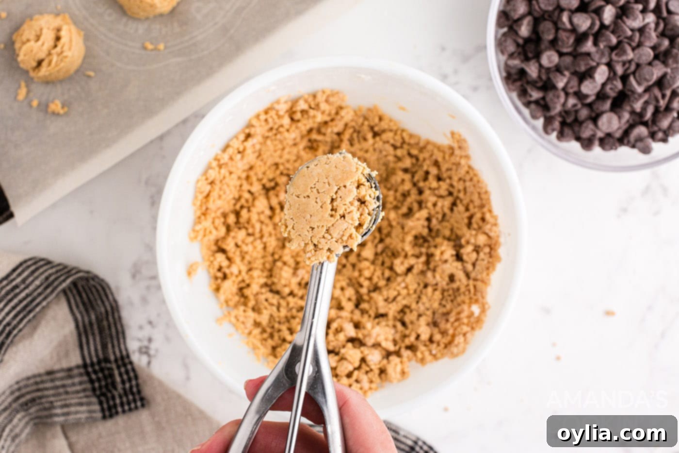 Using a cookie scoop to portion out the peanut butter mixture for consistent sized balls