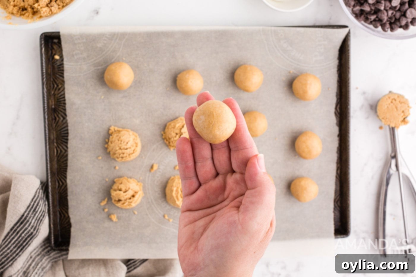 Hand rolling a scoop of peanut butter mixture into a smooth, round ball