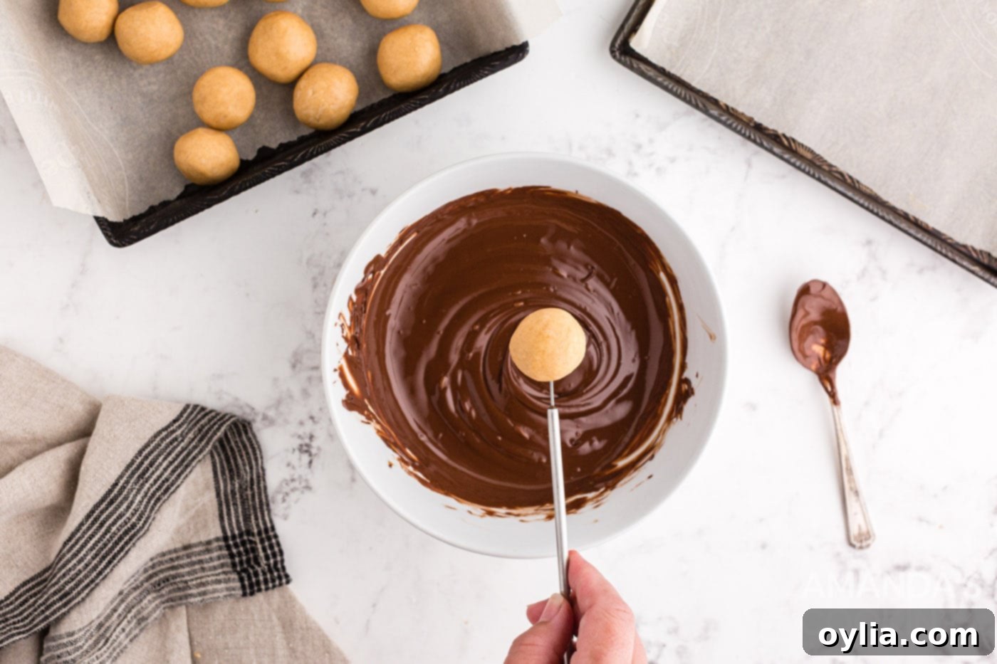 Dipping a peanut butter ball into melted chocolate for even coating