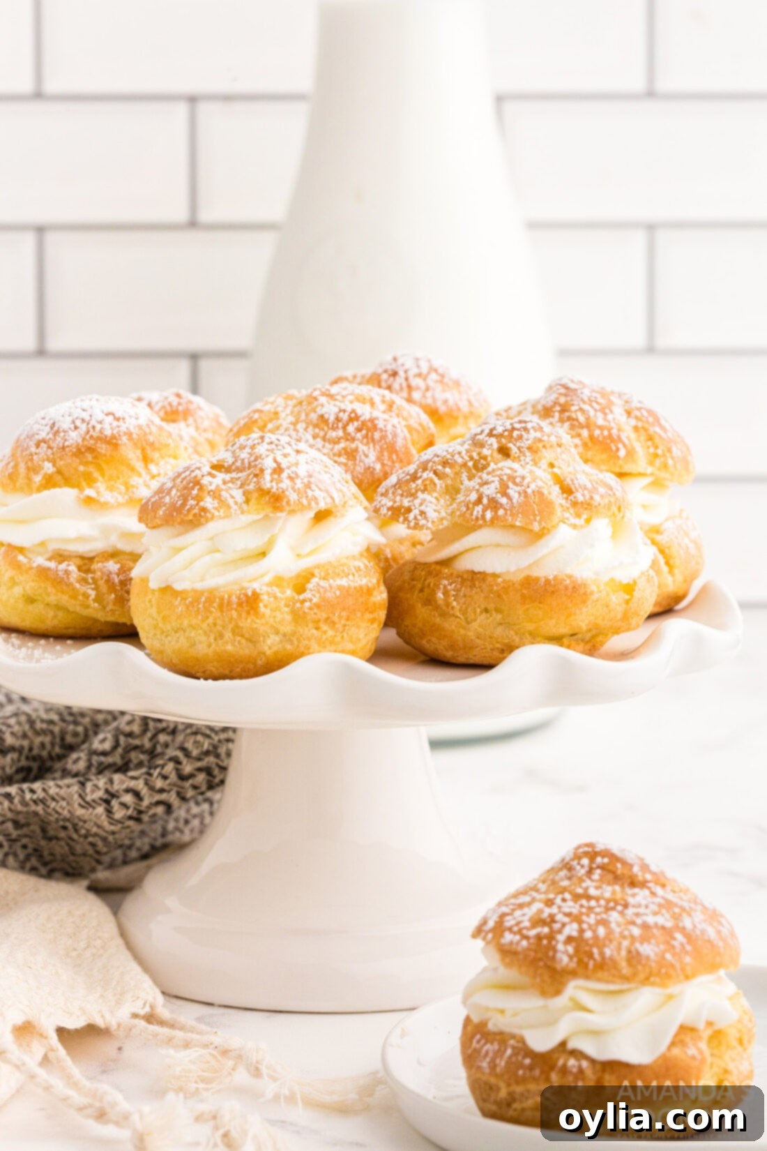 A beautiful display of homemade cream puffs on a cake plate