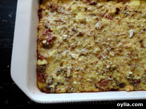 An overhead shot of a glorious, freshly baked Herbed Breakfast Stuffing Casserole, showcasing its golden-brown top, melted cheese, and aromatic herbs.